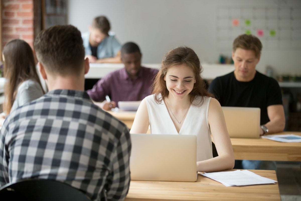Une jeune femme souriante travaillant sur un ordinateur portable dans un bureau de coworking